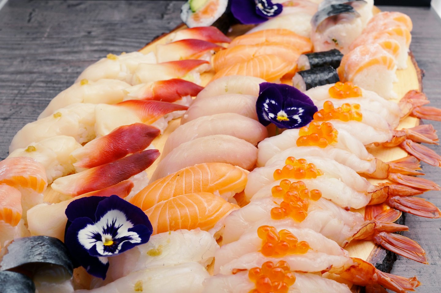 Assorted sushi and sashimi arranged on a wooden board.
