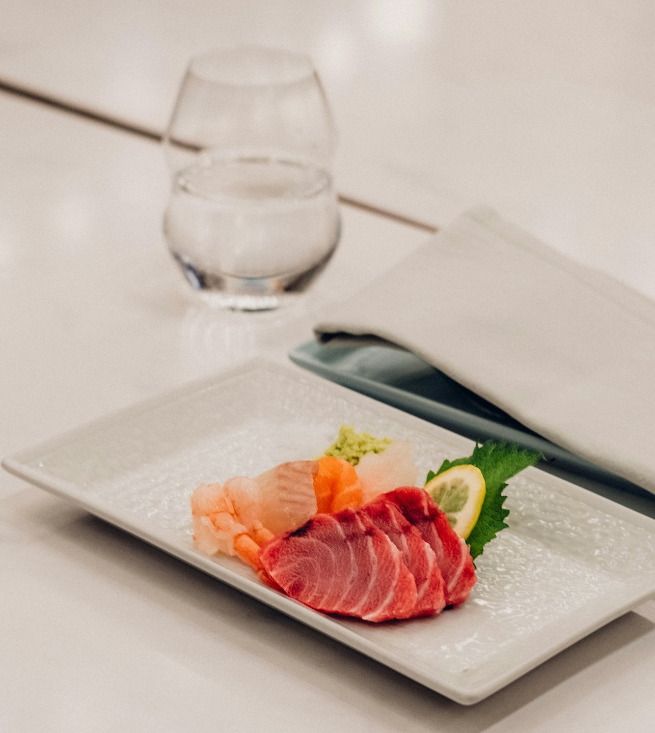 Assorted sashimi on a white rectangular serving plate.