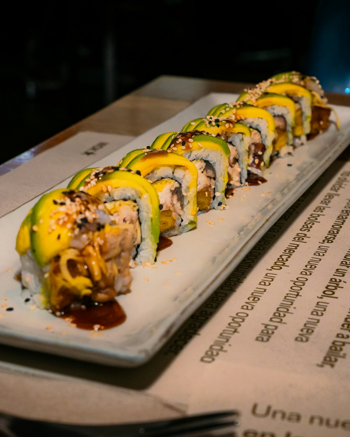 Dragon rolls topped with avocado and sesame seeds on a plate.