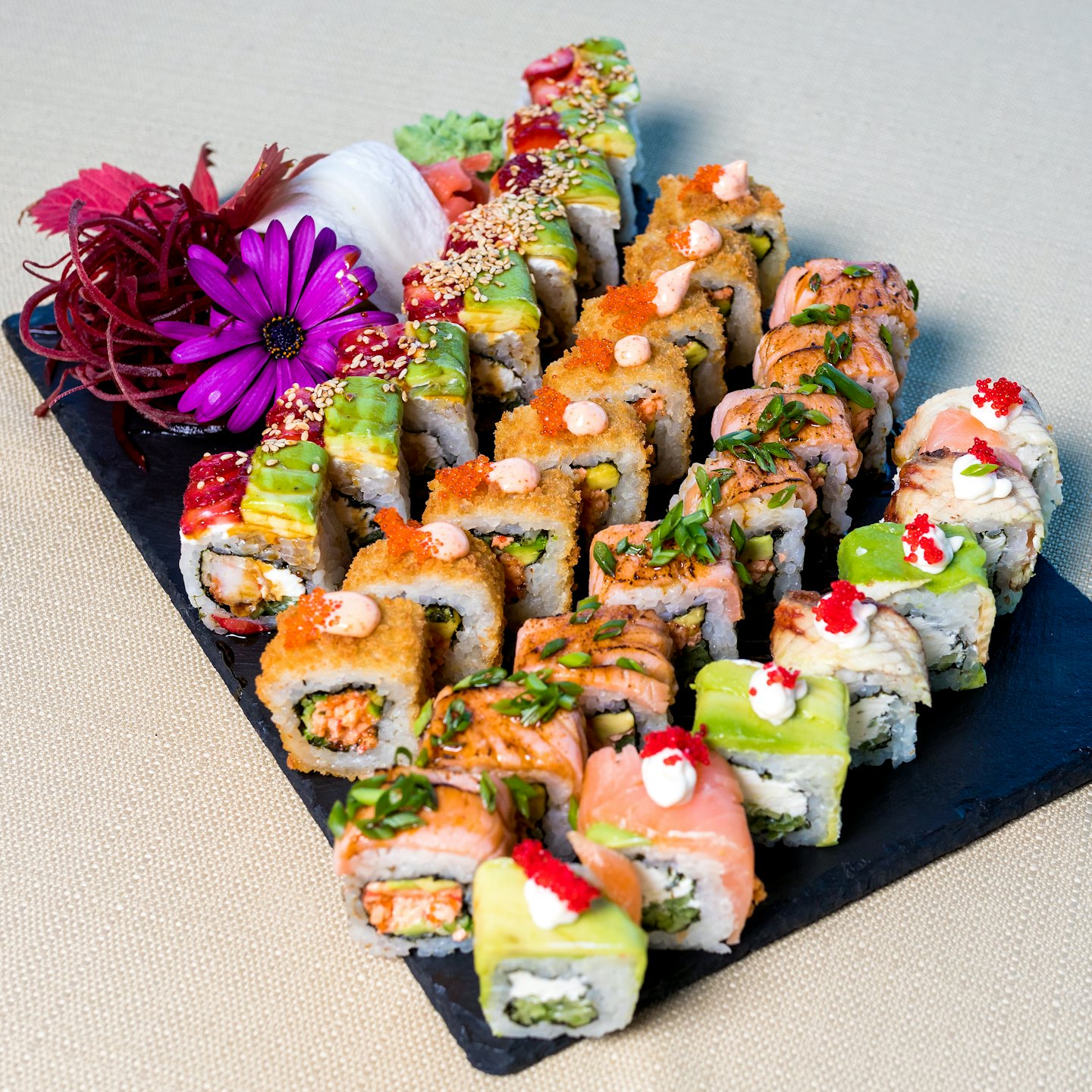 Colorful sushi platter with salmon, avocado, and tempura rolls.