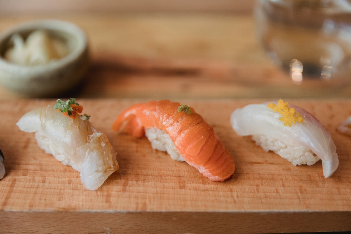 Three pieces of nigiri sushi sit on a wooden board.